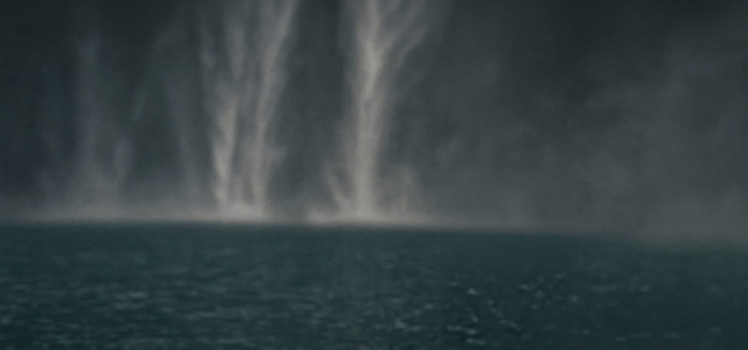 Mist rising off a waterfall over dark water